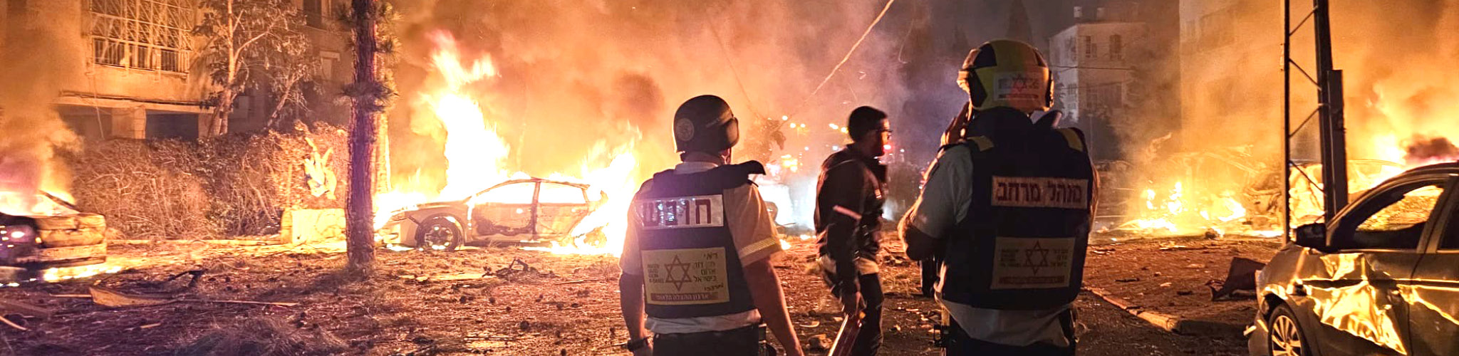 Emergency service workers in front of burning buildings, cars, and rubble